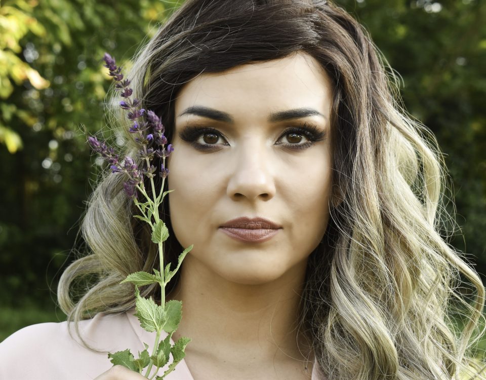 beautiful woman with Spring hair colors, outdoors holding a lavender flower
